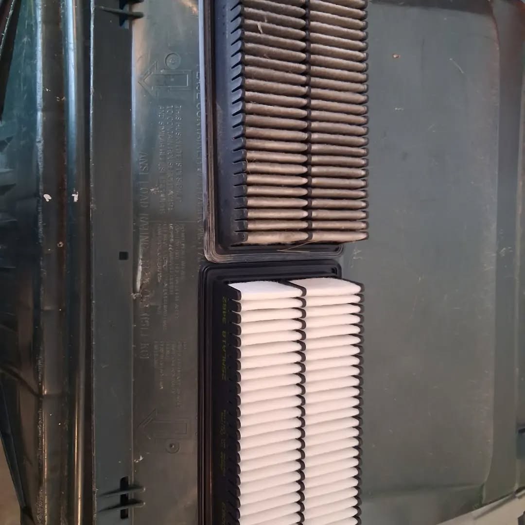 Dirty old engine air filter next to a clean new replacement