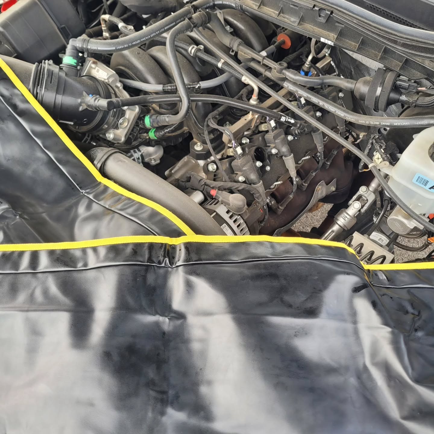 Ford F-250 engine bay with a fender cover protecting the paint during service