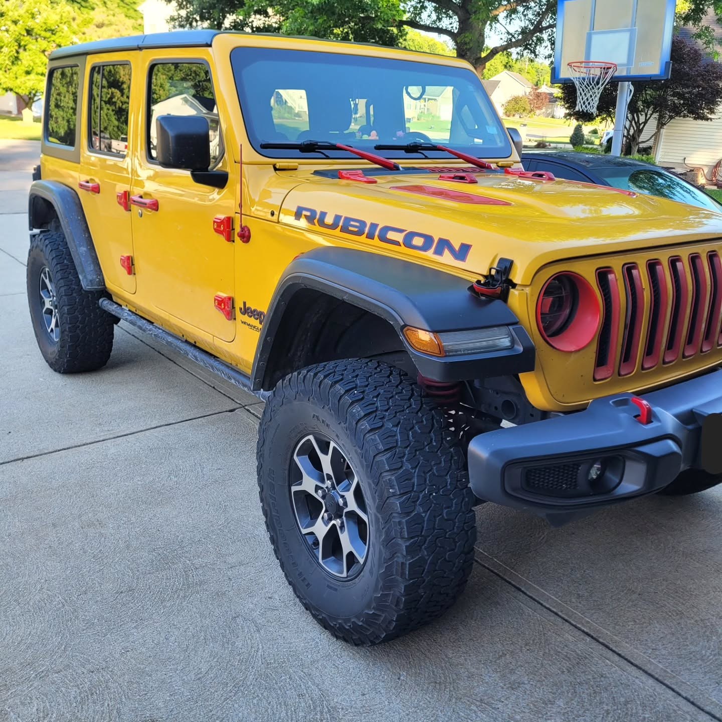 Yellow Jeep Wrangler Rubicon parked on a driveway, seen from the front