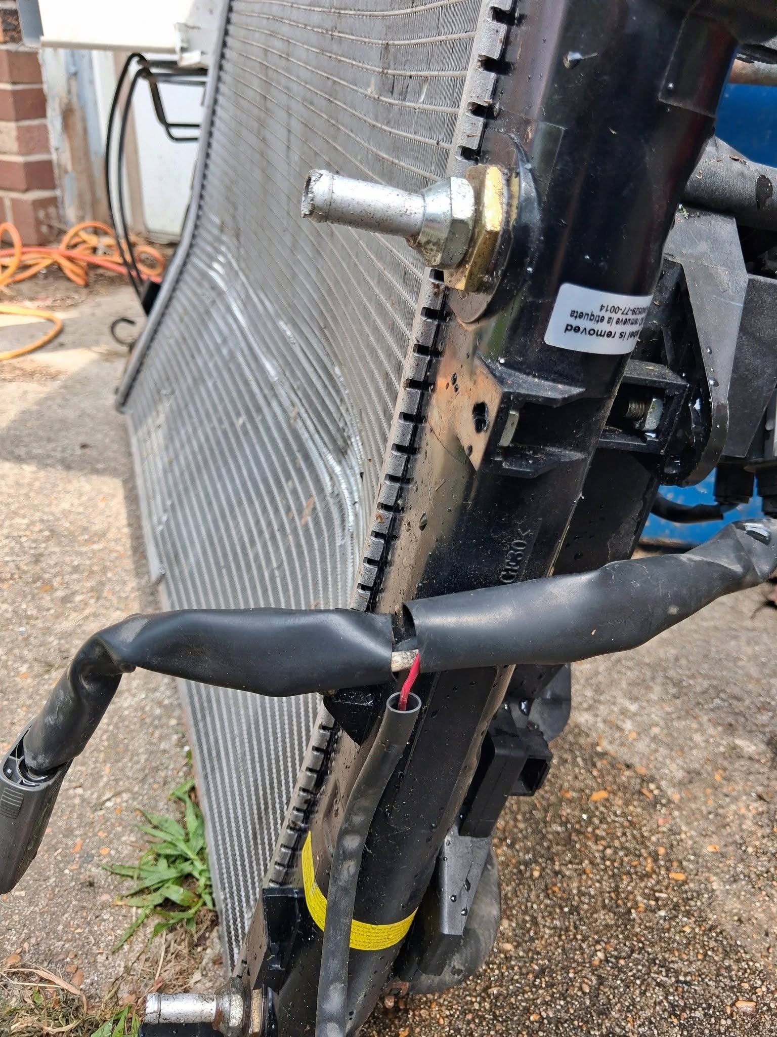 New aluminum radiator with hoses propped against a curb