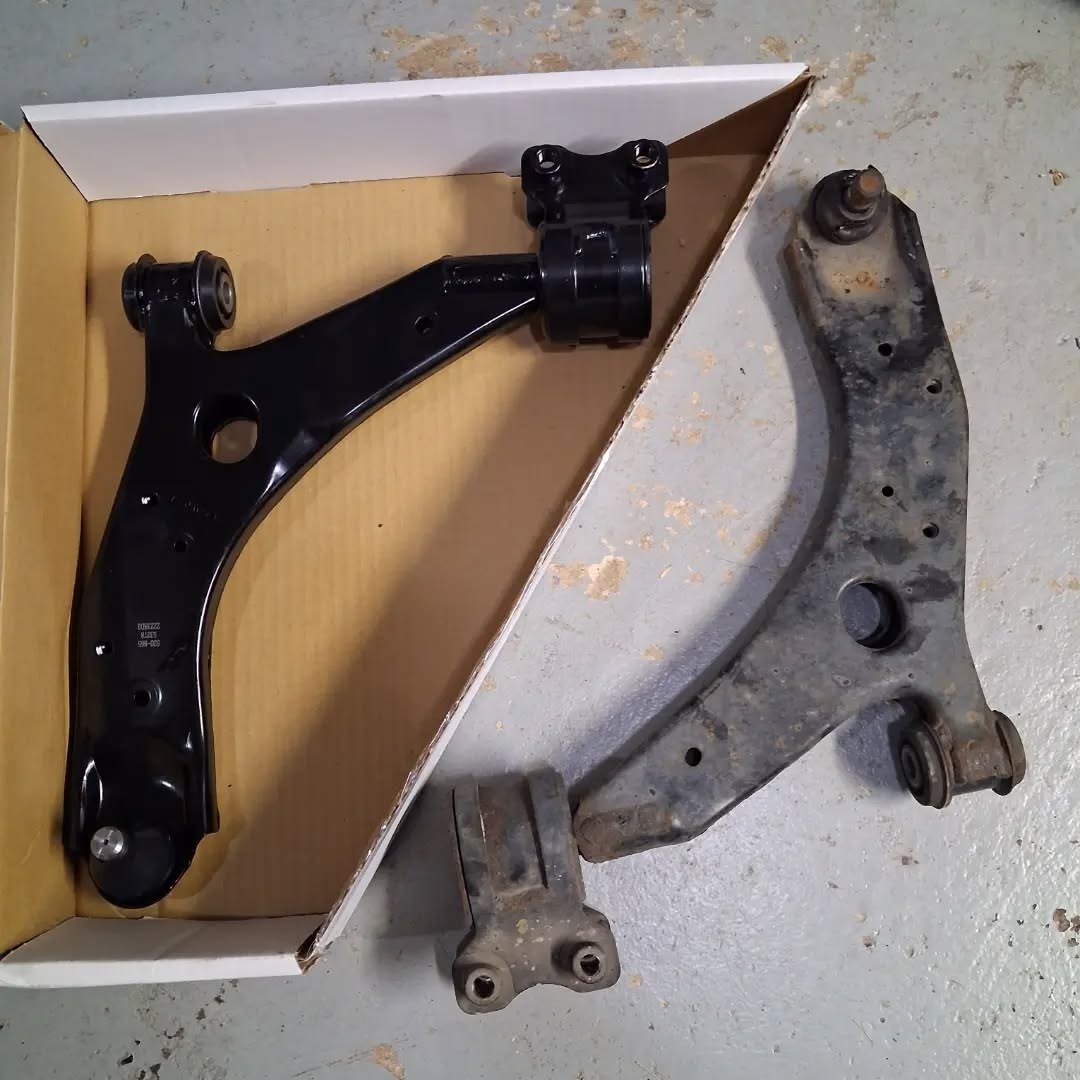 New lower control arm in its box beside the worn original part